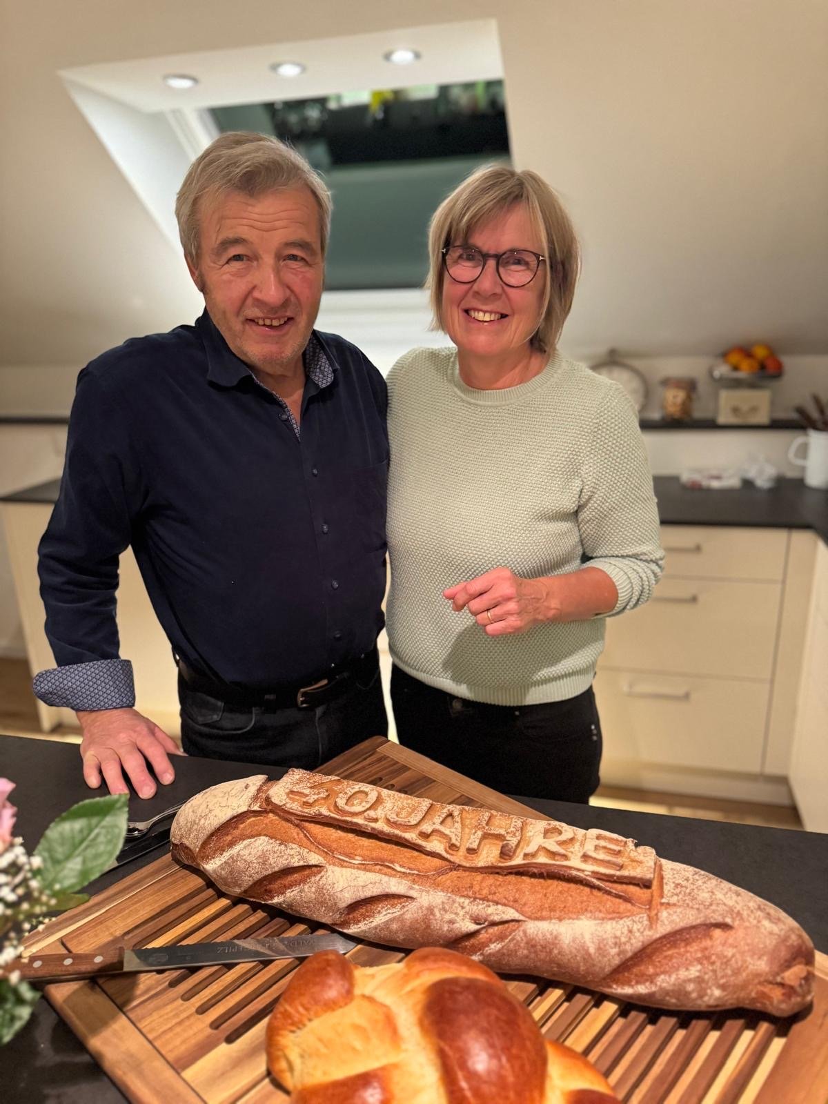 Dani und Margrit Ammann in ihrer Küche, vor ihnen ein Brot mit der Aufschrift 40 Jahre